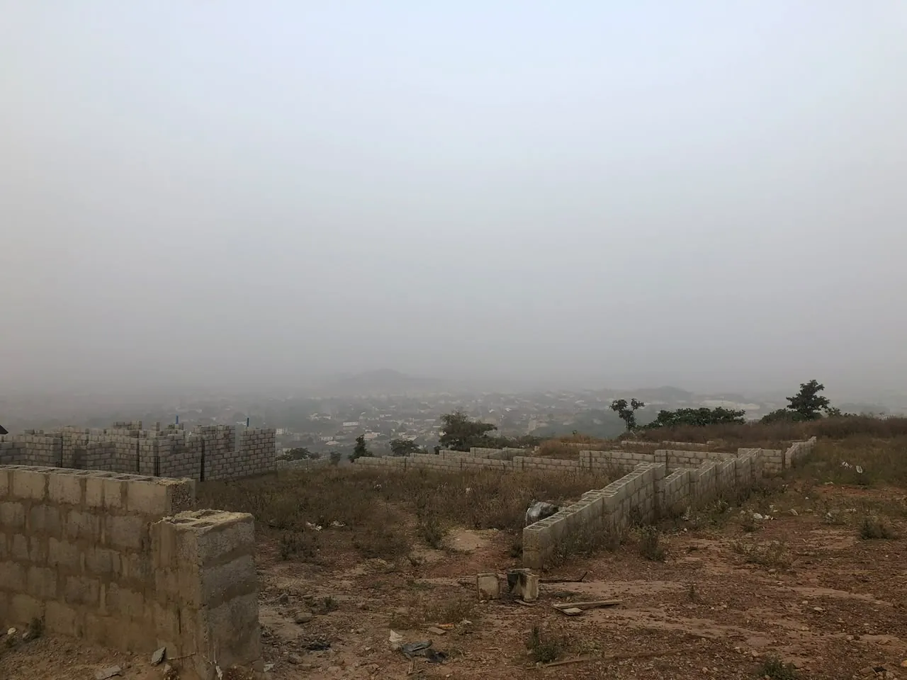 Hilltop plots with foundation blockwork overlooking the city in morning haze